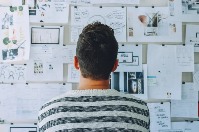 Man looking at whiteboard full of layout sketches.